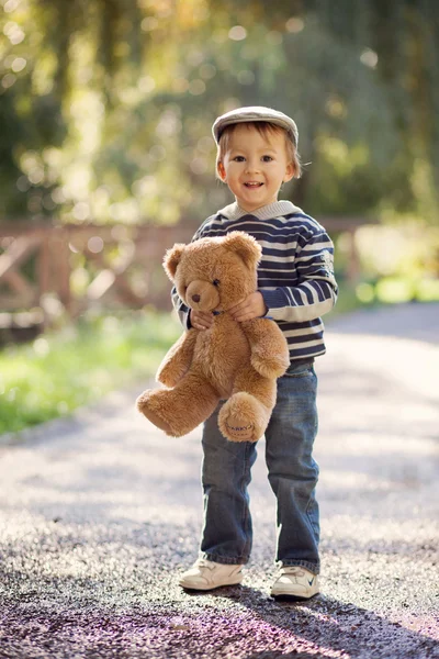 Jongen met een teddybeer in een park — Stockfoto