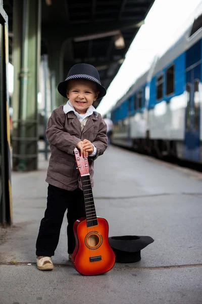 Мальчик с гитарой на железнодорожной станции — стоковое фото