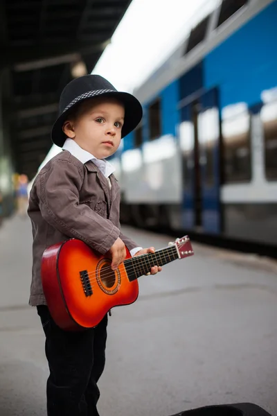 Rapaz com uma guitarra numa estação ferroviária — Fotografia de Stock