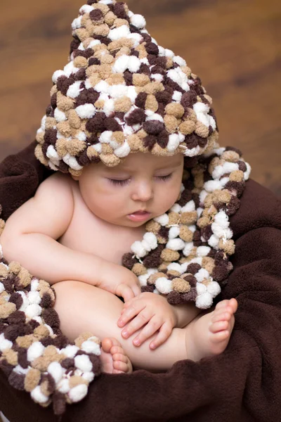 Niño en una cesta con sombrero y bufanda — Foto de Stock