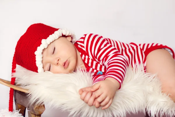 Little baby boy, dressed in santa clothes, sleeping on a sledge — Stock Photo, Image