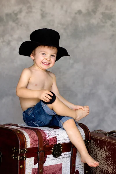 Ragazzo con un cappello, seduto sul petto — Foto Stock