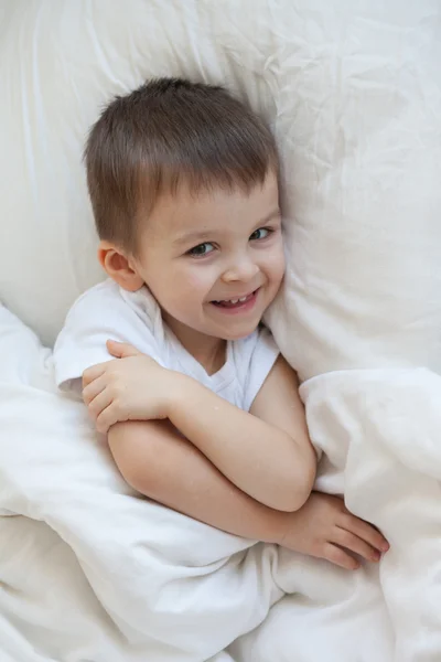 Boy, lying in bed, smiling — Stock Photo, Image