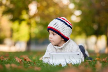 Tablet bir bahçede oynayan çocuk,