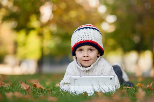 Jongen, spelen op Tablet PC op een gazon — Stockfoto