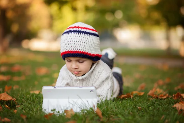 Tablet bir bahçede oynayan çocuk, — Stok fotoğraf