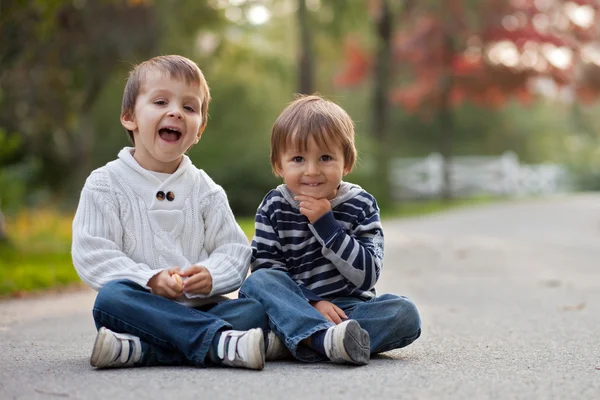 Deux garçons dans un parc, assis sur le sol — Photo