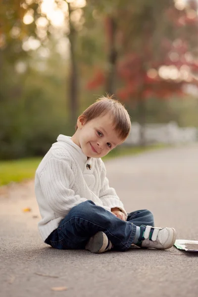 Αγόρι, κάθεται σε μια πορεία σε ένα πάρκο — Φωτογραφία Αρχείου
