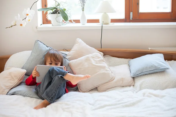 Junge, auf dem Bett liegend, spielt mit Tablet — Stockfoto