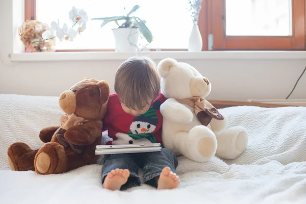 Boy, lying on the bed the bed, playing with tablet — Stock Photo, Image