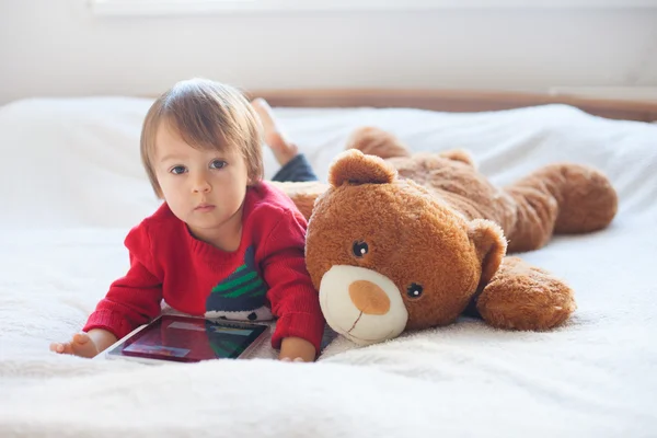 Rapaz, deitado na cama da cama, a brincar com o tablet — Fotografia de Stock