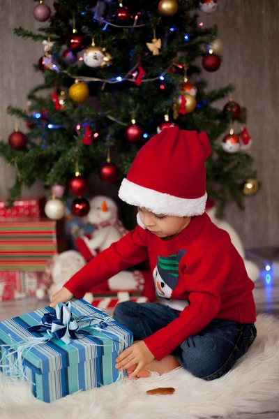 クリスマスのプレゼントを開ける小さな男の子 ストック写真