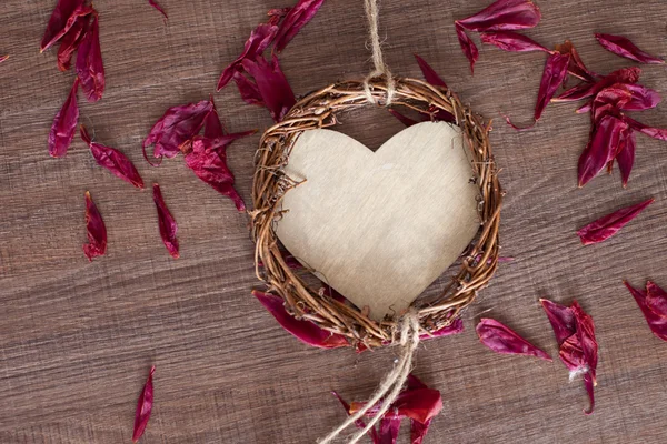 Wooden heart with rose leaves — Stock Photo, Image