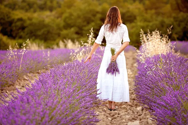 Hermosa joven, sosteniendo lavanda en un campo — Foto de Stock