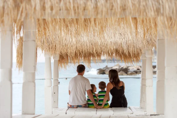 Οπίσθια όψη του μια ευτυχισμένη οικογένεια, που κάθεται στην παραλία, βλέποντας το — Φωτογραφία Αρχείου
