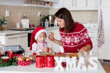Sevimli sarışın çocuk, çocuk ve annesi evde Noel kurabiyesi pişiriyor, eğleniyor.