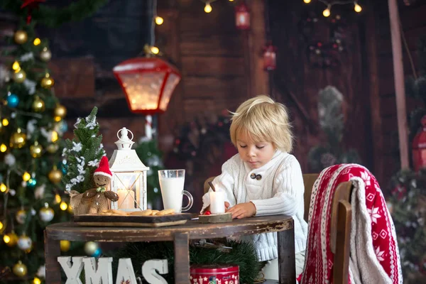 美しい幼児の子供 ブロンドの男の子 サンタクロースへの手紙を書くと自宅でクッキーを食べる クリスマスに居心地の良い雰囲気 — ストック写真