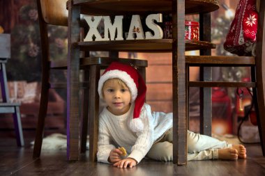 Sevimli çocuk, Noel 'de çocuk, Noel Baba' ya mektup yazıyor ve evde kurabiye yiyor, rahat ahşap kulübe