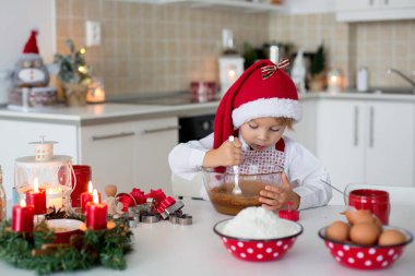 Sevimli sarışın çocuk, çocuk ve annesi evde Noel kurabiyesi pişiriyor, eğleniyor.