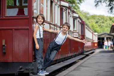 Güzel çocuk, giyinmiş vintage giysiler içinde eski buharlı tren sıcak yaz günlerinde İngiltere'de zevk.