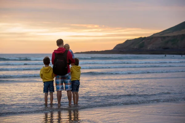 年轻的父亲与他的美丽的孩子 享受夕阳在海洋上的低潮在德文郡 — 图库照片