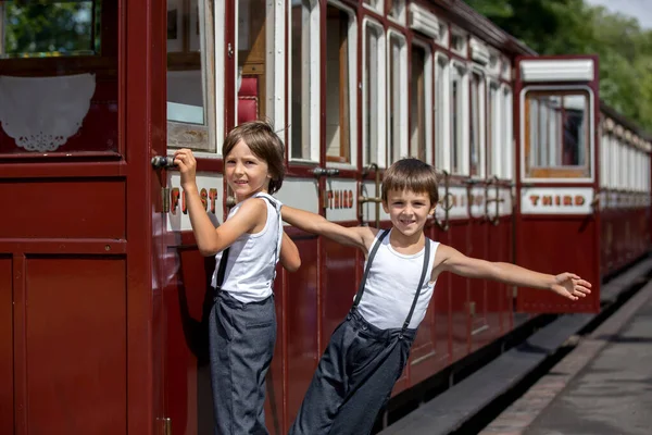 美しい子供 ビンテージの服を着て夏の暑い日にイングランドの古い蒸気機関車を楽しんで — ストック写真