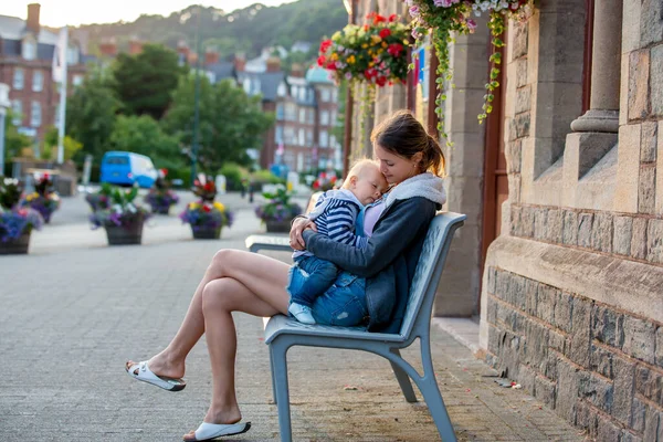 坐在美丽老村中心的长凳上 抱着她的小男孩 微笑着拥抱着 — 图库照片