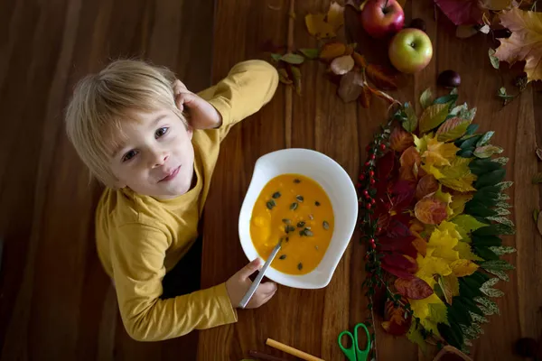 甘い子 男の子 カボチャのスープを食べ 葉を葉で芸術や工芸品をやっている間に接着剤を使用して葉を適用しながら 葉のカラフルなスペクトル — ストック写真