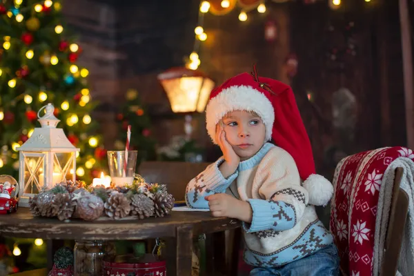 かわいい幼児の子供 クリスマスの出口の男の子 クリスマスに木製の小屋で遊んで 彼の周りの妄想 児童書やお茶を飲む — ストック写真