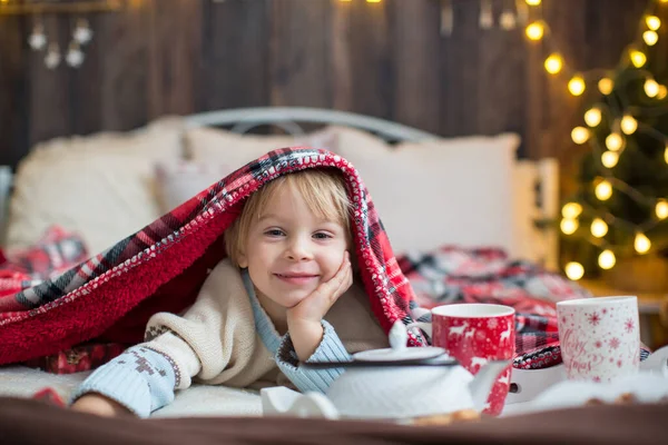 かわいい幼児の子供 クリスマスの出口の男の子 クリスマスに木製の小屋で遊んで 彼の周りの妄想 児童書やお茶を飲む — ストック写真
