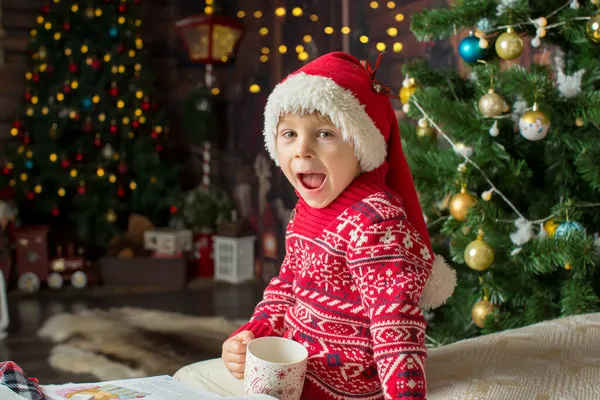 可爱的蹒跚学步的孩子 圣诞节的时候在一个木制的小木屋里玩耍 在他身边打趣 儿童阅读书籍和喝茶 — 图库照片