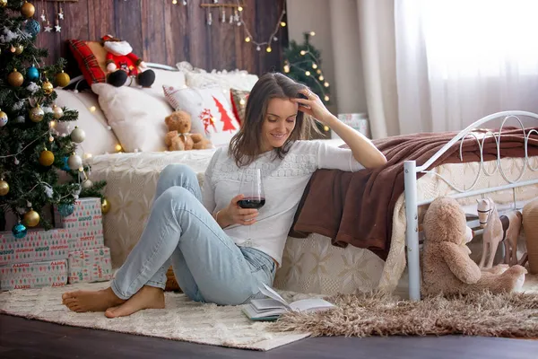 中年妇女在家里喝红酒 在木屋里享受着舒适的圣诞气氛 — 图库照片