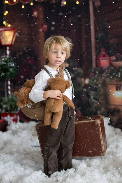 かわいいファッション幼児の男の子 木製のキャビンログ クリスマスの装飾の前にテディベアで雪の中で遊んで — ストック写真