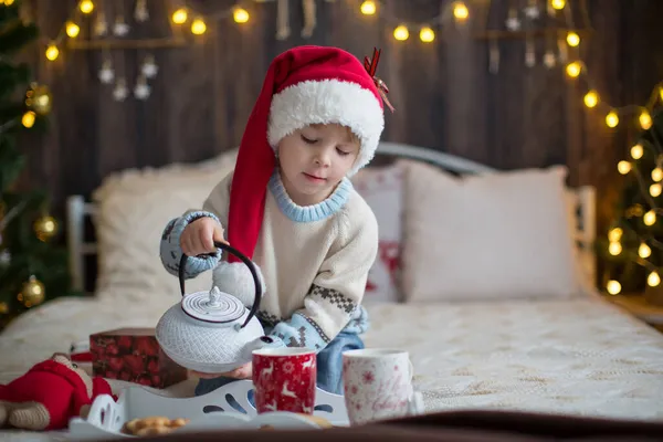かわいい幼児の子供 クリスマスの服の少年 クリスマスの木製キャビンで遊んで 彼の周りの装飾 児童書やお茶を飲む — ストック写真
