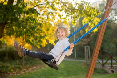 Mutlu çocuklar, sonbahar parkında evcil köpekle oynuyorlar güneşli bir günde, yapraklar ve yapraklar etraflarında.