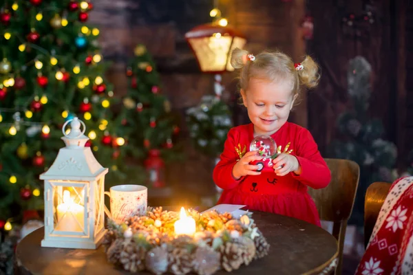 かわいいですブロンドの子供 二つのポニーテールと巻き女の子 クリスマスの装飾とテーブルの上に座って手紙を書くとクリスマスのおもちゃで遊んで — ストック写真