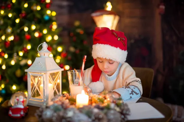 かわいい幼児の子供 クリスマスの服の少年 クリスマスの木製キャビンで遊んで 彼の周りの装飾 児童書やお茶を飲む — ストック写真