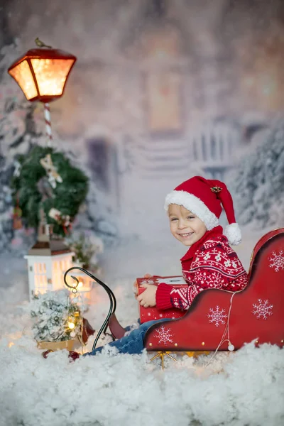 かわいい幼児ブロンドの子供 男の子 屋外でそりに座って 雪の冬のシーン 彼の周りのクリスマスの装飾 — ストック写真
