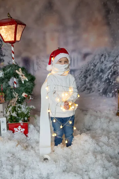 かわいい幼児の男の子 ブロンドの子供 家の前に立って クリスマスの文字列のライトやトイレの紙に包まれ 閉じ込められた感じ — ストック写真
