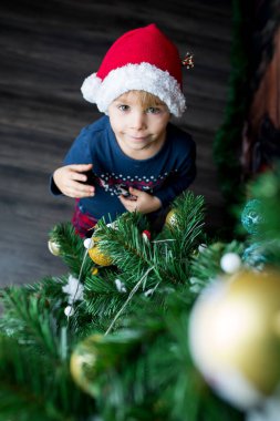 Sevimli çocuk, oğlum, Noel ağacını oyuncaklarla süslüyorsun.