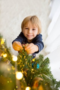 Sevimli çocuk, oğlum, Noel ağacını oyuncaklarla süslüyorsun.