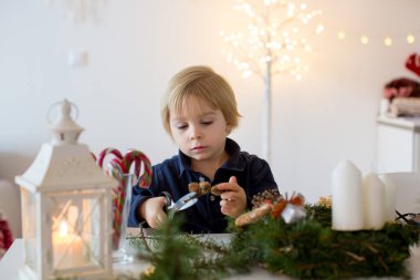 Küçük tatlı sarışın çocuk, oğlum, evde Noel çelengi süslüyor.