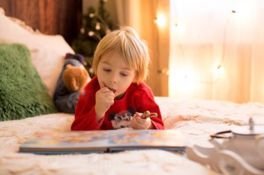 Sarışın çocuk, yeni yürümeye başlayan çocuk, Noel 'de evde eğleniyor, renkli bastonlarla oynuyor.