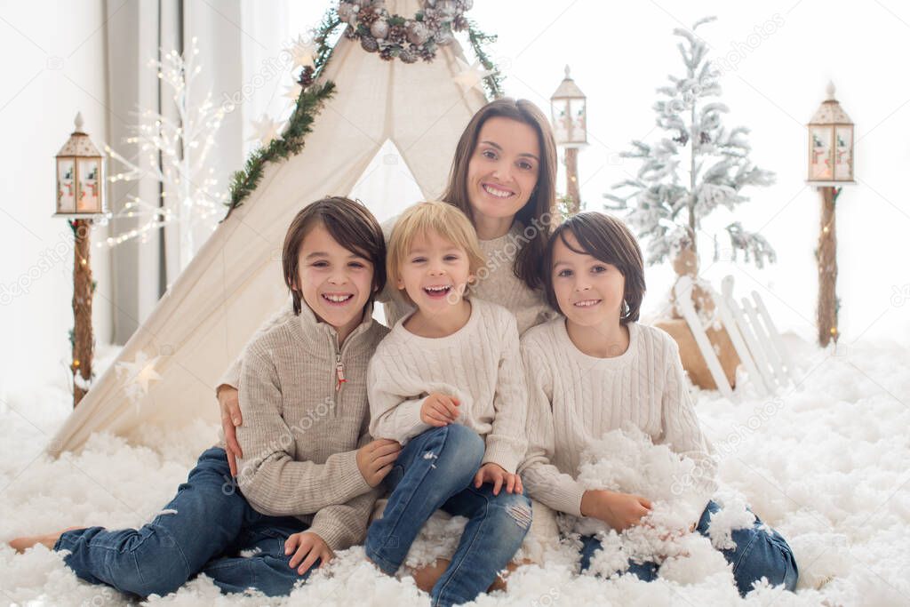 Happy family, children and mom, enjoying christmas together in cozy home, decorated with christmas decoration