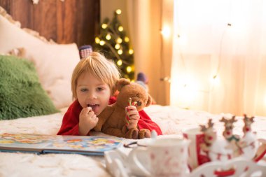 Sarışın çocuk, yeni yürümeye başlayan çocuk, Noel 'de evde eğleniyor, renkli bastonlarla oynuyor.