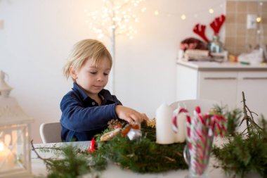 Küçük tatlı sarışın çocuk, oğlum, evde Noel çelengi süslüyor.