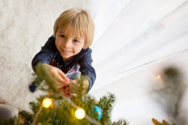 Sevimli çocuk, oğlum, Noel ağacını oyuncaklarla süslüyorsun.