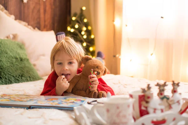 Sarışın çocuk, yeni yürümeye başlayan çocuk, Noel 'de evde eğleniyor, renkli bastonlarla oynuyor.