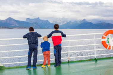 Çocuklar, sevimli çocuklar Norveç 'te bir feribottan dağlara bakıyor.