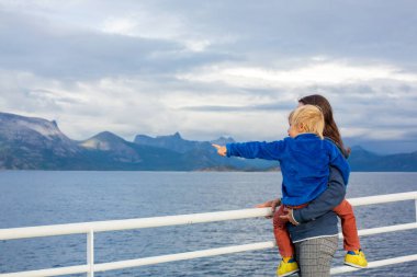 Çocuk ve anne, annesiyle birlikte sevimli sarışın çocuk Nortern Norveç 'te bir feribottan dağlara bakıyor.